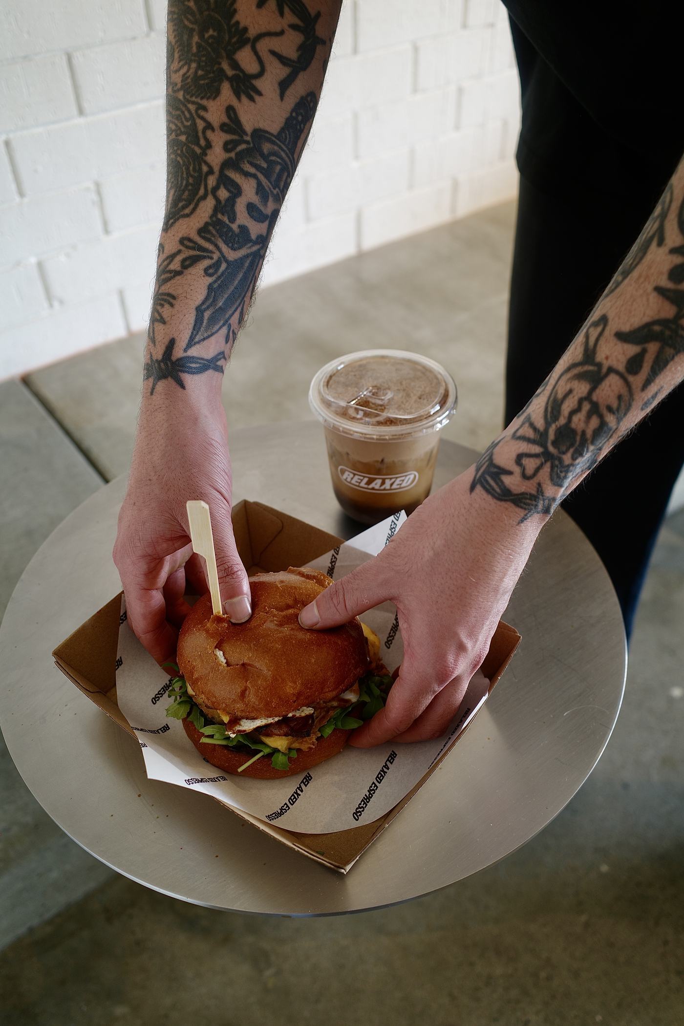 Brekky burger and iced coffee handed over the counter