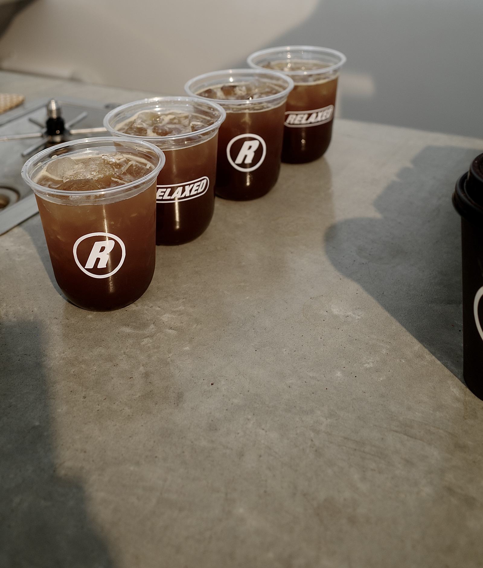 Iced long blacks lined up in branded Relaxed Espresso cups