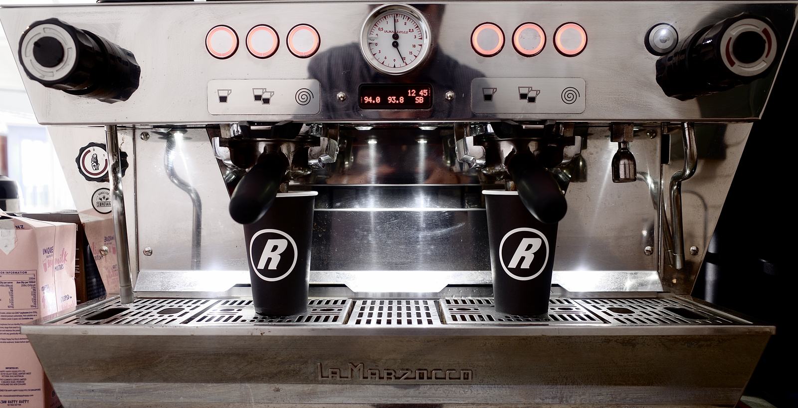 The La Marzocco espresso machine with R-branded cups under the group heads