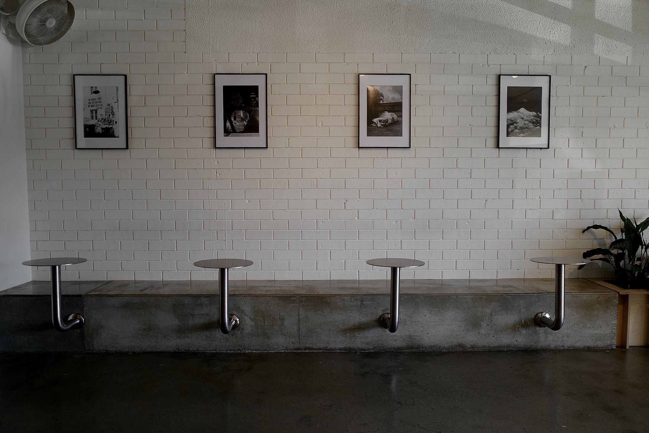 Relaxed Espresso interior — the concrete bench, steel tables and framed film prints in moody light